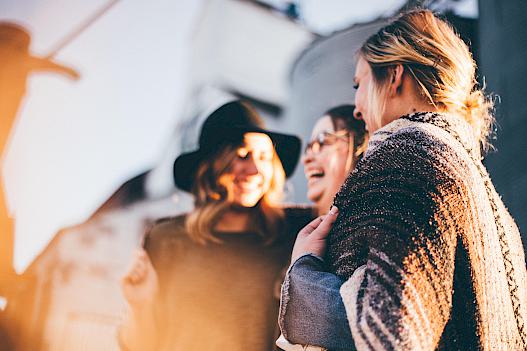 3 junge Frauen stehen lachend zusammen